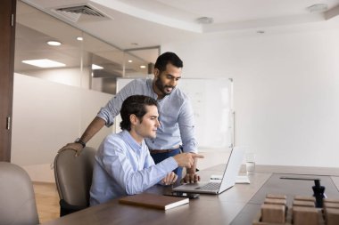 Dizüstü bilgisayar ekranına bakan iki erkek meslektaşı, toplantı odasında ortak bir tartışma ya da takım çalışması yapıyorlar. İspanyol adam görevi soruyor, akıl hocalığına yeni bir şirket yazılımı. Yardım, çıraklık.