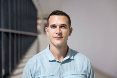 Yakışıklı Avrupalı iş adamının yakın çekimleri, günlük mavi gömlekler giyen yönetici yönetici içeride poz veriyor, kameraya bakın, boş ofis koridorunda ya da koridorda durun. İş adamı portresi