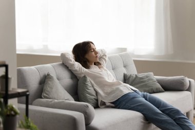 Uykulu, yorgun, yetişkin bir kız. Oturma odasında dinleniyor, rahat bir koltukta oturuyor, dinleniyor, dinlenirken kollarıyla uyuyor, vücudunu esnetiyor, boş zamanların tadını çıkarıyor.