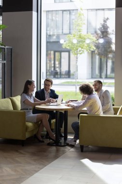 Mutlu genç ve hırslı iş adamları modern ofiste masalarında oturup gülüyor, beyin fırtınası yapıyor, iş fikirlerini birlikte tartışıyor, gülümsüyor, eğleniyor, şakalaşıyor, takım brifinginde müzakere ediyor.