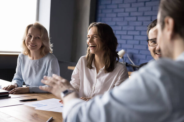 Joyful diverse business colleagues discussing funny creative idea on office corporate meeting with partners, laughing, having fun. Happy different aged coworkers brainstorming on training