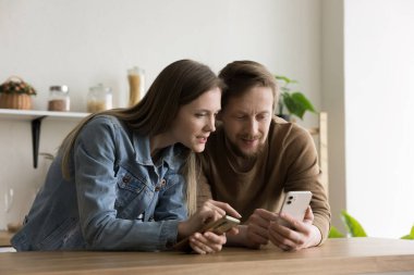 Akıllı telefonlar kullanarak, medya içeriğini paylaşarak, çevrimiçi ve çevrimdışı iletişimden zevk alarak, mutfak masasına yaslanarak, cep telefonlarını tutarak,