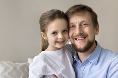 Sevgi dolu bir baba kucağında tatlı bir kız çocuğu, yanak teması ile kucaklayan bir çocuk, dişlek bir gülümsemeyle kameraya bakıyor. Küçük güzel bir kızın portresi. Sevgili babasına sevgiyle sarılıyor.