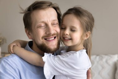 Mutlu, rahat bir babanın yüz portresi, kucağında barışçıl, küçük, tatlı bir kız çocuğu, gözleri kapalı kucaklıyor, rahatlamanın, huzurun, aşkın, sevginin, şefkatin, şefkatin tadını çıkarıyor.