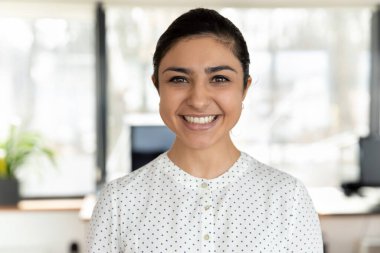 Modern ofisteki iş yerinde gülümseyen Hintli genç kadın pozunun portresi. Milenyum karışık ırk kadın çalışanlarının profil fotoğrafı güven gösteriyor. İstihdam kavramı.