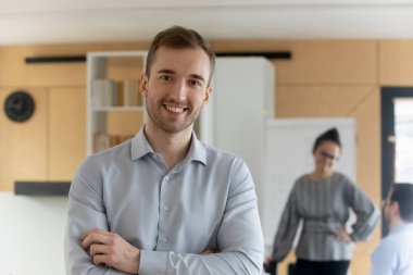 Kameraya bakıp gülümseyen beyaz iş adamının portresi iş yerinde güven ve liderlik gösteriyor. Mutlu genç erkek çalışan ya da işçi pozu. İstihdam, işe alım kavramı.