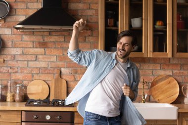 Coşkulu, kaygısız bir adam dans ediyor, evdeki rahat mutfağa taşınıyor, aktif, heyecanlı bir erkek tek başına eğleniyor, ilk daireye taşınmayı kutluyor, boş zamanların tadını çıkarıyor.