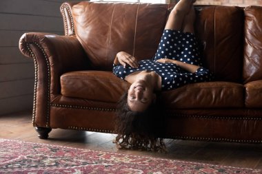 Gülümseyen, güzel bir kadın rahatlayan, rahat koltukta baş aşağı uzanan, evde tek başına tembel boş vakit geçiren, mutlu, genç bir bayan hayal kuran ve güzel bir geleceği hayal eden, kanepede dinlenen