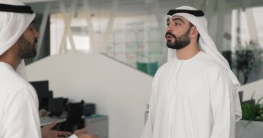 İki yakışıklı Arap erkek iş ortağı modern ofiste el sıkışıyor, karlı, ticari anlaşmalar yapıyor, gülümsüyor, başarılı bir pazarlığın sonucundan tatmin oluyorlar.