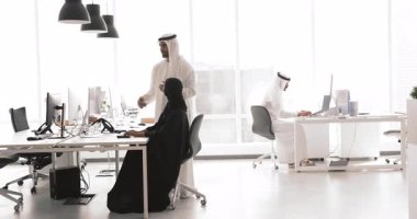 İki Arap takım arkadaşı birlikte çalışarak ortak online projeyi tartışıyor, ekrana işaret ediyor, detayları veya çözümleri tartışıyor, bilgi sağlıyor, fikir alışverişinde bulunuyor, ofiste beyin fırtınası yapıyor