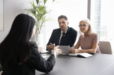 Arkadan bakan kadın başvuru sahibi şirket ofisinde iş görüşmesini geçiyor, konuşma yapıyor, iki İK yöneticisinin önünde oturmuş soruları cevaplıyor. Kelle avı, müzakere süreci