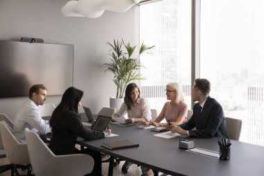 İş konularını, stratejiyi veya yeni proje detaylarını tartışan bir grup profesyonel, işbirliği toplantısı, beyin fırtınası oturumu veya stratejik kararlar ve takım çalışmasını içeren müzakereler sırasında