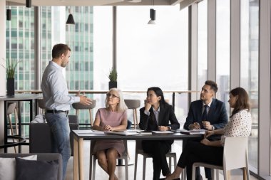 Modern ofiste profesyonel toplantı. Şirket yöneticisi hissedarların önünde konuşma yapar, bilgi verir, açıklamalar yapar, yeni proje detaylarını sunar, iş stratejilerini tartışır