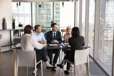 Bir grup işadamı modern ofiste iş toplantılarına katılıyor, konferans masasında oturuyorlar ve dostane bir ortamda olumlu tartışmalara giriyorlar. İşbirliği, beyin fırtınası, müzakere etkinliği