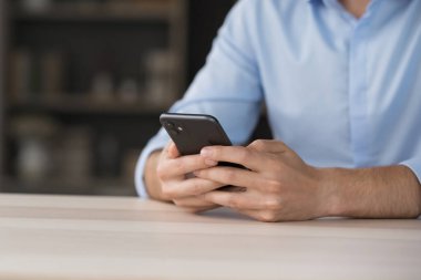 Telefon uygulamasında çalışıyorum. Yakın çekim yapan genç adam, masadaki cep telefonunu elinde tutarak internet yönetimi görevleri ile iletişim kurarak ekranda sürekli bağlı kalan mesaj metnini oluşturuyor. Boşluğu kopyala