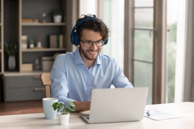 Sanal etkileşim. Mutlu Gen Z ofis çalışanı kablosuz kulaklıklar takan serbest çalışan öğrenci video konferansında iş arkadaşlarıyla iletişim kurar not defteri kullanarak online sınıfta bilgi toplar.