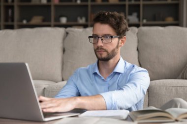 Genç yetişkin uzak öğrenme. Portre odaklı gen z adam uzak öğrenci çevrimiçi çalışma oturum sıcak ev ofis dijital ve kağıt araçlar kullanarak bilgi kitap türü Not Defteri okuma