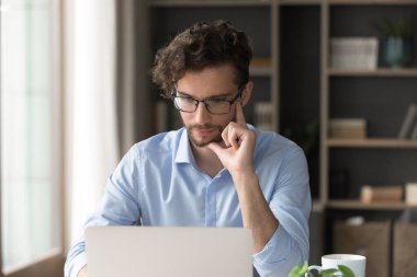 Teknolojiyle sorunu çözmek. Genel merkezde internet üzerinde çalışan düşünceli, serbest çalışan erkek öğrenci. Sorun çözümü üzerinde düşün. Proje detaylarını düşün.