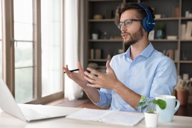 Online eğitim. Kulaklıklı kendine güvenen erkek öğretmen, notlardaki sanal sınıf uygulaması ile sınıfa veya öğrencilere öğrenme materyallerini açıklar. Milenyum öğrencisi, video görüşmesinde özel öğretmen sorusuna cevap verdi