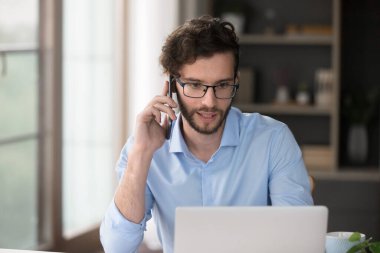 Müşteri iletişimi. Konsantre olmuş milenyum erkek yönetici danışmanı uzaktan müşteriyle telefon gözden geçirme bilgileri üzerinde çalışıyor. Not ekranı öneri desteği sunma hizmeti ürünlerin satılmasına yardımcı oluyor