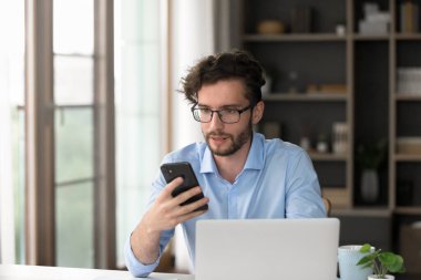 Melez iletişimi. Ev ofisinden öğrenim gören genç ve meşgul bir erkek işletme öğrencisiyse bilgisayardaki projeyi tamamlamak için internet üzerinden bilgi araması için ai telefon uygulamasına yardımcı olur.