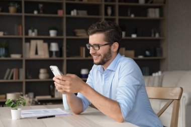 İşe ara verdim. Mutlu Gen Z erkek uzaktan çalışan çalışan çalışan öğrenci ev ofis masasında dijital iletişimde çalışıyor. Evrak işleri rutininden dikkati dağılmış telefondaki kısa mesaj.