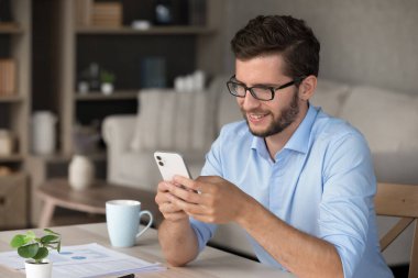 Telefon uygulaması kullanıyor. Portre başarılı genç serbest çalışan işadamı cep telefonu ekranında cep telefonu mesajlarını okuyup şifreleme işlemleri için kullanım uygulamasının keyfini çıkarıyor. Boşluğu kopyala