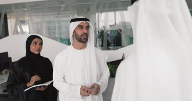 Geleneksel kandora gibi giyinmiş bir grup profesyonel Arap iş adamı, etkili iş ilişkilerini sıkı bir el sıkışma, güven ve saygı jesti ile sonuçlandırdılar.