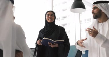 Liderlik, güçlendirme, profesyonel iletişim. Siyahlı abaya 'lı kadın defterini tutuyor, özgüvenle konuşuyor, fikirlerini, noktalarını ve çözümlerini iki erkek meslektaşıyla paylaşıyor.