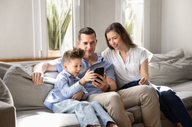 İlgilenen oğul cep telefonuyla yeni bir oyun öğreniyor ebeveynleri ve ailesi ile kanepeye oturuyor, eğitim amaçlı mobil uygulama kullanıyor, internette zaman geçiriyor. Ebeveynler küçük 8 'li yaşlardaki çocuklara modern aletler kullanmayı öğretiyor.