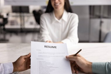 Pozitif kadın iş başvurusunda bulunan kadının iş görüşmesinde iki acemi yöneticiyle konuşması bulanık arka planda masada oturması, özgeçmişi tartışması, gülümsemesi.