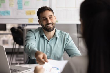 Mutlu genç İspanyol proje yöneticisi kağıt satışları pazarlama raporunu iş ortağına sunuyor, masanın üzerinde iş arkadaşına evrak veriyor, gülümsüyor, müzakere toplantısında başlangıç satışı yapıyor.