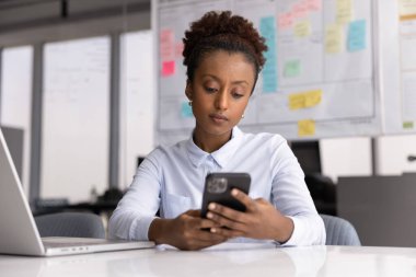 Çevrimiçi iletişim teknolojisi kullanan çok güzel bir Afrikalı kadın akıllı telefonda iş başvurusu, kuryeleri kontrol etmek, internette sohbet etmek, cep telefonuyla yazmak.