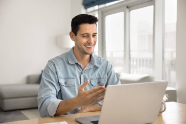 Yakışıklı Latin adam dizüstü bilgisayarla masada oturuyor, aile veya arkadaşla sanal görüşmenin keyfini çıkarıyor, kişisel sohbetlere öncülük ediyor ya da iş görüşmesini uzaktan geçiriyor. Videocall uygulama kullanımı, dijital iletişim