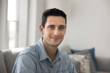 Gündelik tişört giymiş gülümseyen İspanyol bir adamın portresi kameraya poz vermek evde koltukta oturmak, kendi başına tasasız bir hafta sonu geçirmek ya da daire kiralamak. Mutlu ve memnun ev sahibi veya kiracı, profil resmi