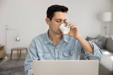 Genç Hispanik adam, modern anavatanda dizüstü bilgisayarla masa başında otururken ya işe başlar ya da en sevdiği içecekle ders çalışmaya başlar. Yaşam tarzı, rutin, iş-yaşam dengesi