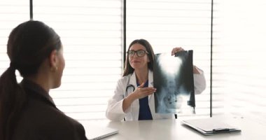Elinde radyografik görüntüleme olan kadın doktor röntgen sonuçlarını açıklıyor, sağlık durumu ve kadın hastalara daha fazla rehabilitasyon hakkında konuşuyor. Teşhis, sağlık, tıbbi danışmanlık