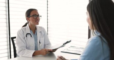 Klinikteki kadınla el sıkışan pratisyen hekim, hastanede randevusu var. Kadın hasta, profesyonel tıbbi bakım ve hizmetleri için şükran ve takdirlerini sunuyor.