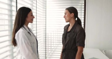 Palto giymiş kadın doktor muayene odasında duran kadın hastayla el sıkışıyor başarılı bir muayeneyi tamamlıyor ve özel klinikte işe yarar bir randevu ayarlıyor. Sağlık hizmetleri