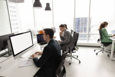 İş yerinde iş arkadaşlarıyla bilgisayar kullanan, boş boş monitöre bakan, klavyede yazan bir finans uzmanı. Şehir içi ofis için çalışan başarılı finans şirketinin personeli