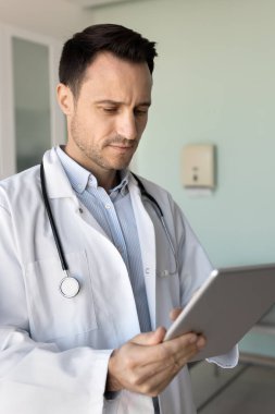 Doktor iş yerinde tablet kullanıyor, tıbbi makaleyi araştırıyor, bilgileri araştırıyor, hasta randevularını yönetiyor, tedavi planlarını izliyor, müşterilere uzaktan tele sağlık platformu üzerinden danışmanlık yapıyor.