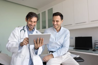 Tablet kullanan pozitif doktor, laboratuvar, röntgen veya tarama gibi mutlu hasta test sonuçlarını gösteriyor, etkili tedavi planını açıklıyor, tıbbi prosedürler gösteriyor, sağlık sorunları hakkında iyi haberler paylaşıyor