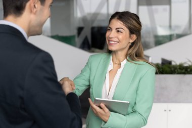 Neşeli İspanyol iş kadını erkek patronun, ortağın, takım liderinin elini sıkan, iş arkadaşına el sıkışan, gülümseyen, kapanış anlaşması, iş görüşmesi, danışmanlık için teşekkür eden.