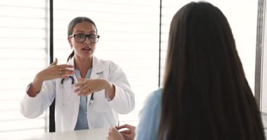 Beyaz önlük giymiş profesyonel kadın pratisyen doktor kadın hastalara sağlık testlerinin sonuçlarını açıklıyor, tedavi planını paylaşıyor, tavsiye veya tavsiye veriyor. Sağlık, ilaç.