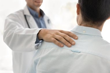 Tanımlanamayan doktor eli hastaların omzuna yakın çekim. Rahatlık, cesaret ve güven göstergesi olarak. Kardiyolog sağlıksız hastalara empati, güven ve duygusal destek sağlıyor.