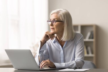 Stratejik vizyon. Düşünceli orta yaşlı iş kadını ofis masasına oturmuş, dikkati dağılmış bir şekilde planlar yapıyor sorunlu çözümleri yeni fikirler üzerinde düşünüyor.