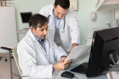 İki kardiyolog doktor tıbbi belgeyi inceliyor, hasta bakımında muayene edilen test sonuçlarını analiz ediyor, tanı veya tedavi planını tartışıyor. Bilgi paylaşımı, karar verme, takım çalışması