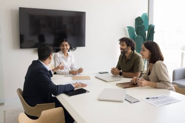 Olumlu, dost canlısı takım arkadaşları brifinge katılırlar, gülerler, hoş sohbetler ederler, işle ilgili yaratıcı fikirleri tartışırlar, çözümleri paylaşırlar, toplantı odasındaki seminerde fikir alışverişinde bulunurlar.