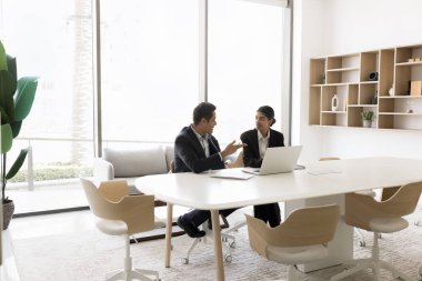 Modern konferans salonunda iki Hintli olgun ve genç iş arkadaşı iş ile ilgili sorunları çözüyor, ortak proje geliştirme ve yeni fikirler üzerinde tartışıyorlar, başlatılıyorlar, ortak görev tamamlama üzerinde çalışıyorlar