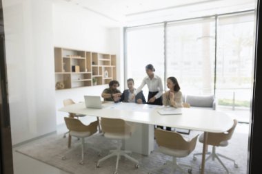 Çeşitli ofis çalışanları modern konferans odasındaki kapalı kapılar ardında brifinge katılıyor, işbirliği toplantısına katılıyor, aktif olarak tartışma, takım çalışması ve karar verme sürecine katılıyor.